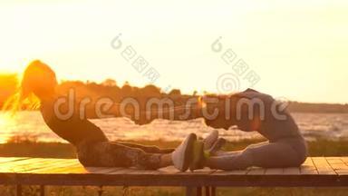 两个年轻漂亮的女孩在日出或日落前在海边的沙滩上脱衣服